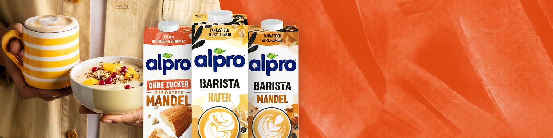 Frühstück mit Kaffee und Müsli neben Alpro Mandelmilch Verpackung