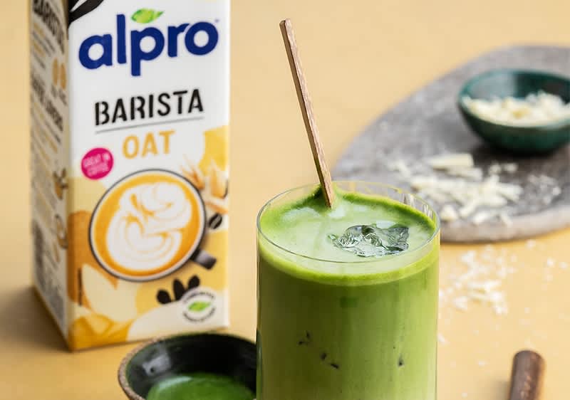 Matcha Latte mit Eis und Alpro Barista Haferdrink im Hintergrund