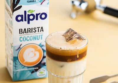 Kokosnuss Latte mit Alpro Barista Verpackung im Hintergrund