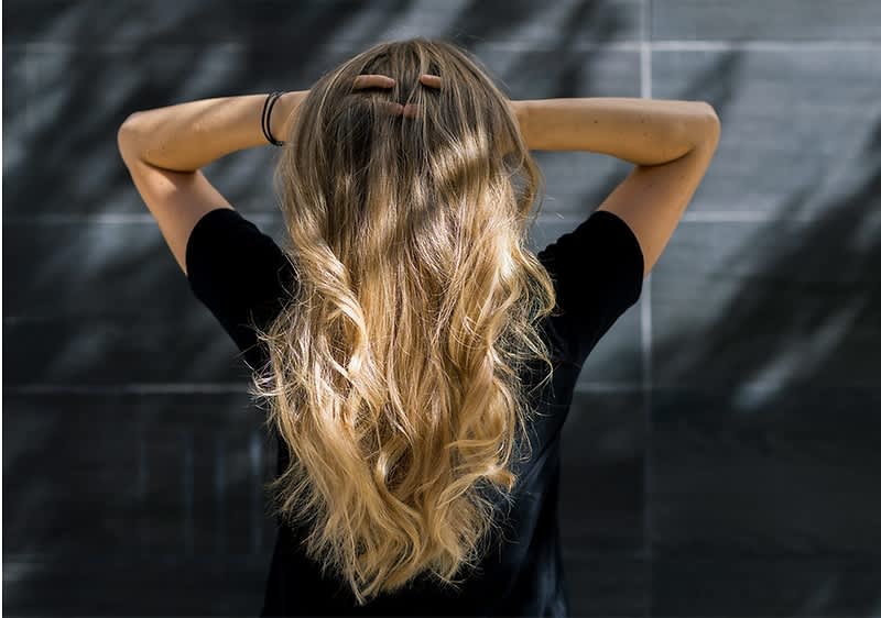 Frau mit langen blonden Haaren von hinten