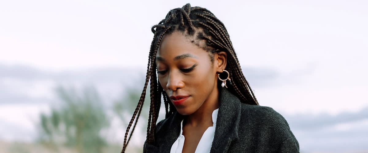 Frau mit geflochtenen Haaren und Ohrringen im Freien