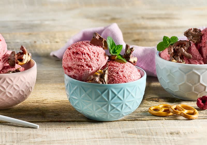 Eiscreme in Schalen mit Himbeeren und Minze auf Holztisch