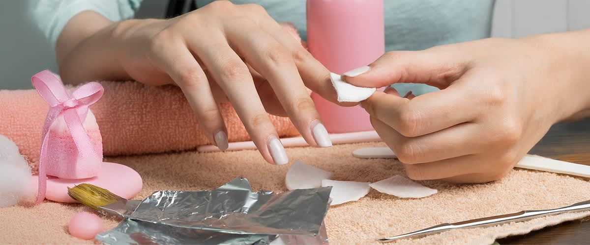 Nagelpflege mit Wattepads und Folie auf Handtuch