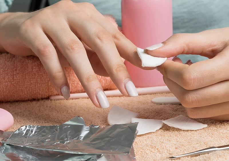 Nagelpflege mit Wattepads und Alufolie auf Handtuch
