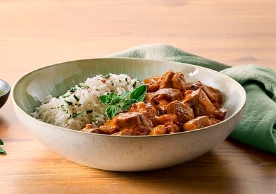 Tikka Masala mit Reis in einer Schüssel auf Holztisch