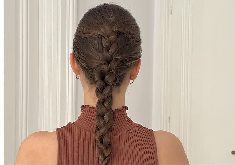 Flechtfrisur mit Zopf auf braunhaariger Frau in ärmellosem Oberteil