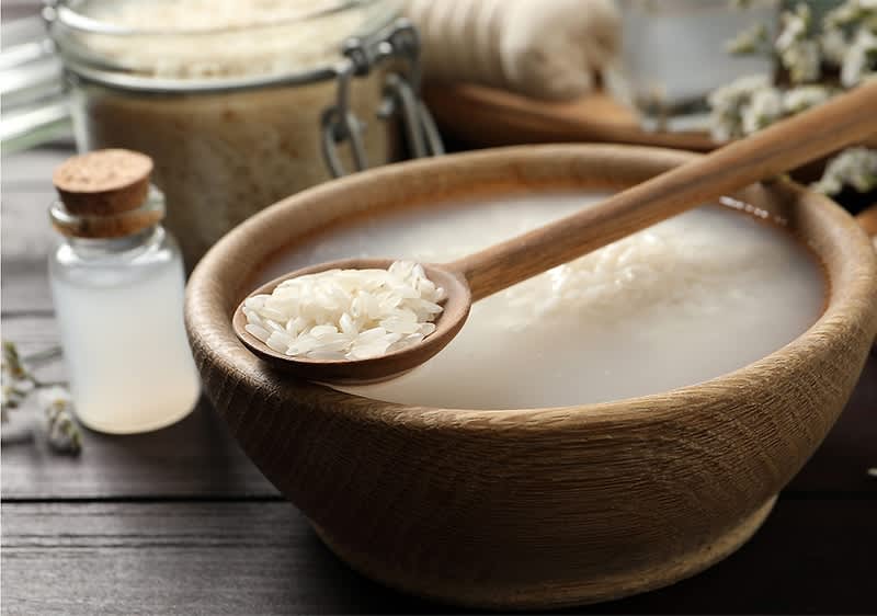 Reiswasser in Holzschale mit Löffel und Glasbehälter
