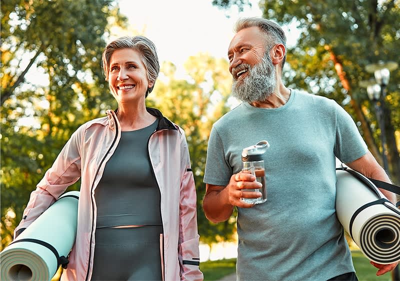 Senioren beim Yoga im Park mit Matten und Wasserflasche