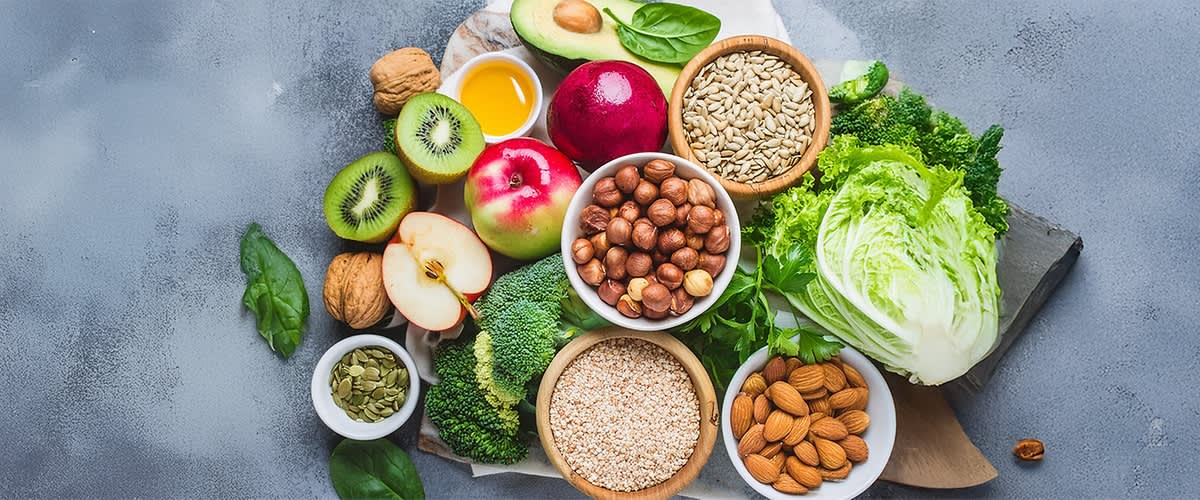 Gesunde Lebensmittel wie Obst Gemüse Nüsse und Samen auf einem Tisch