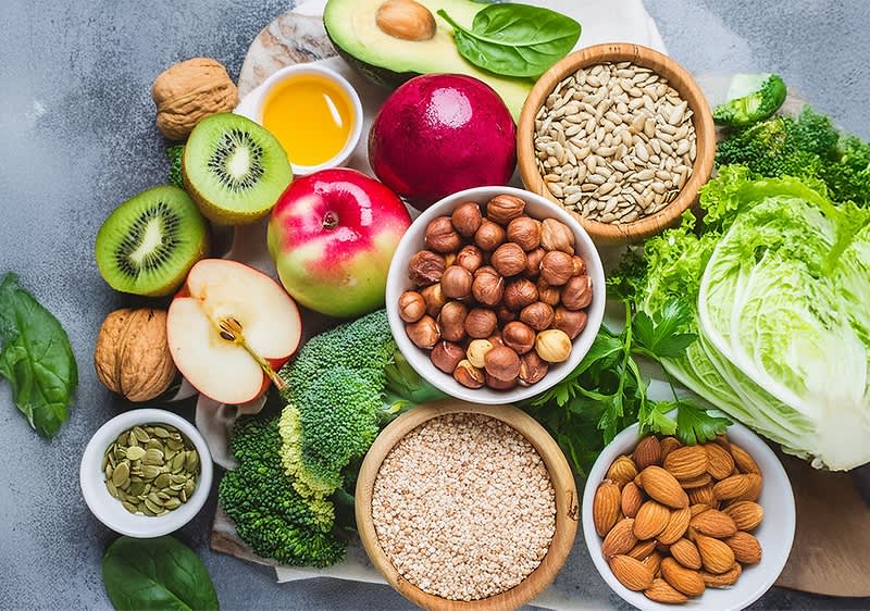 Gesunde Lebensmittel wie Obst, Gemüse, Nüsse und Samen auf einem Tisch