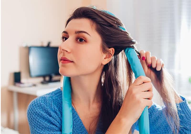 Frau wickelt Haare mit Lockenwickler in einem Raum