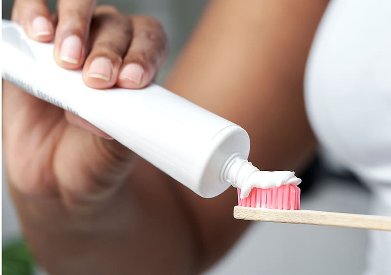 Zahnpasta auf Zahnbürste in Hand