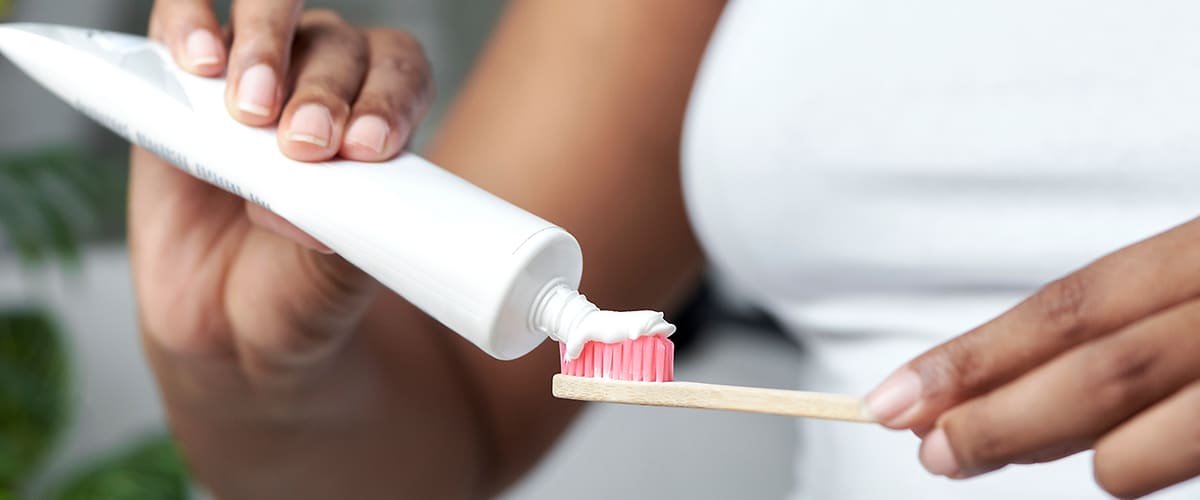 Zahnpasta auf Zahnbürste in Hand