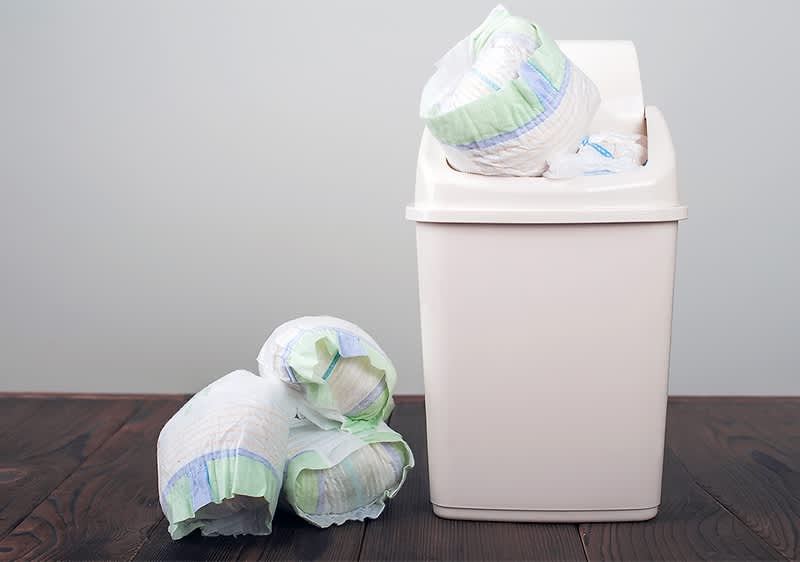 Windeleimer mit Windeln auf Holzboden