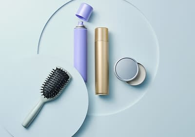 Haarpflegeprodukte auf einem Tisch mit Bürste und Sprühflaschen