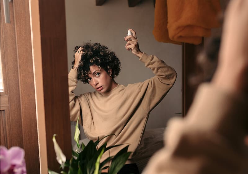 Haarstyling im Spiegel mit Pflanze im Vordergrund