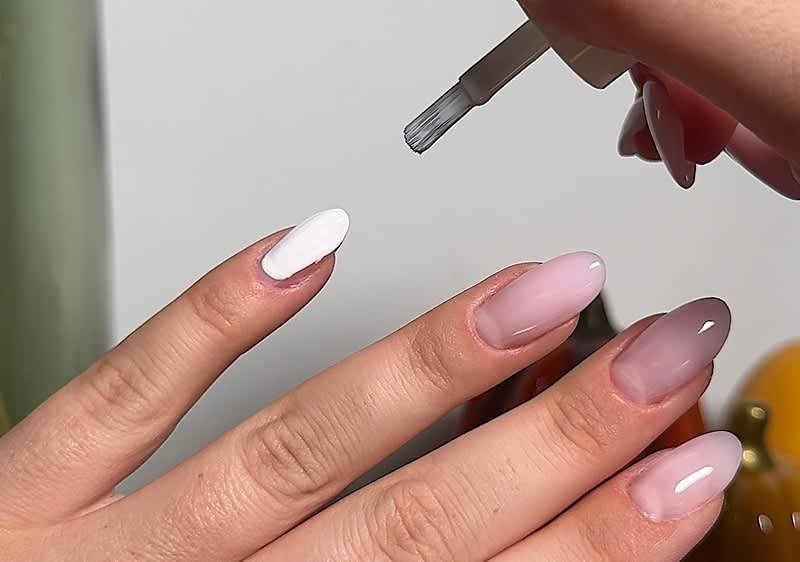 Weißer Nagellack wird auf den Fingernägel aufgetragen