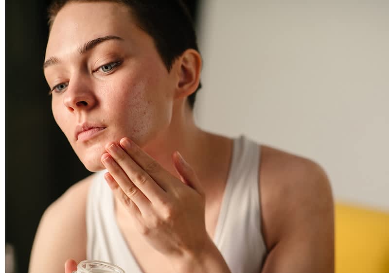 Frau mit kurzen Haaren cremt sich das Gesicht ein