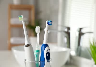 Elektrische Zahnbürsten im Badezimmer vor Waschbecken und Handtüchern