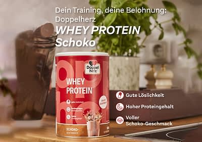 Whey Protein Schoko von Doppelherz auf Küchentisch mit Schokoladenstücken und Pflanzen im Hintergrund