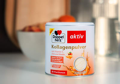 Eine Dose Kollagenpulver von Doppelherz aktiv mit Vitamin C, Zink und Biotin, 20 Portionen, steht vor einer Schale mit Obst