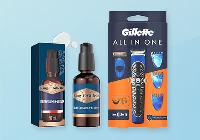 Eine Verpackung von King C. Gillette Bartvolumen-Serum neben einer Gillette All-in-One Rasierer-Set-Verpackung auf blauem Hintergrund