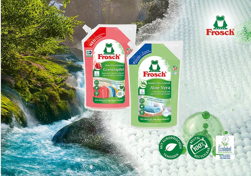 Zwei Frosch-Nachfüllbeutel für Waschmittel, links rot mit Aufschrift „Granatapfel“ und rechts grün mit Aufschrift „Aloe Vera“, darüber das Frosch-Logo, im Vordergrund grüne Kappe und Symbole für 100% recyceltes Material und Ökolabel, im Hintergrund Wasserfall und Fluss. Bild mit AI erstellt
