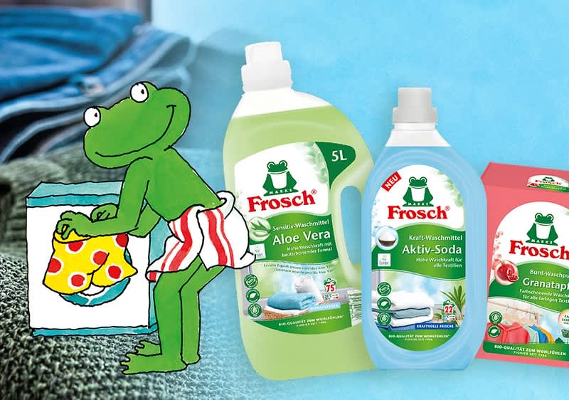 Illustration eines grünen Frosches in gestreifter Hose, daneben Frosch Waschmittel Aloe Vera, Aktiv-Soda und Granatapfel Verpackungen