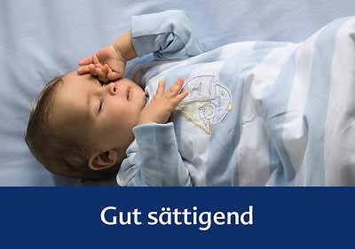 Ein Baby in einem gestreiften Schlafanzug liegt auf einer blauen Decke, darunter der Text „Gut sättigend“
