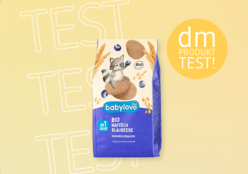 Eine Packung babylove Bio Haffeln Blaubeere mit einem Waschbär-Illustration, daneben ein gelber Kreis mit „dm PRODUKT TEST!“