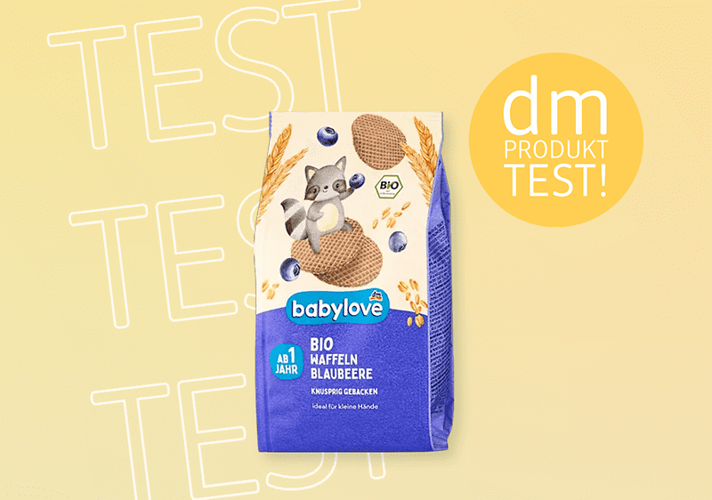Eine Packung babylove Bio Haffeln Blaubeere mit einem Waschbär, blauen Beeren und der Aufschrift „dm Produkttest“ auf gelbem Hintergrund