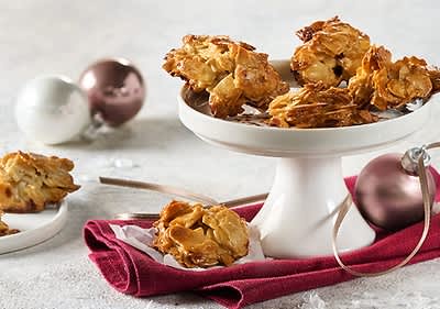 Florentiner Kekse mit Mandeln auf einer weißen Tortenplatte, daneben liegen Weihnachtskugeln und ein rotes Tuch