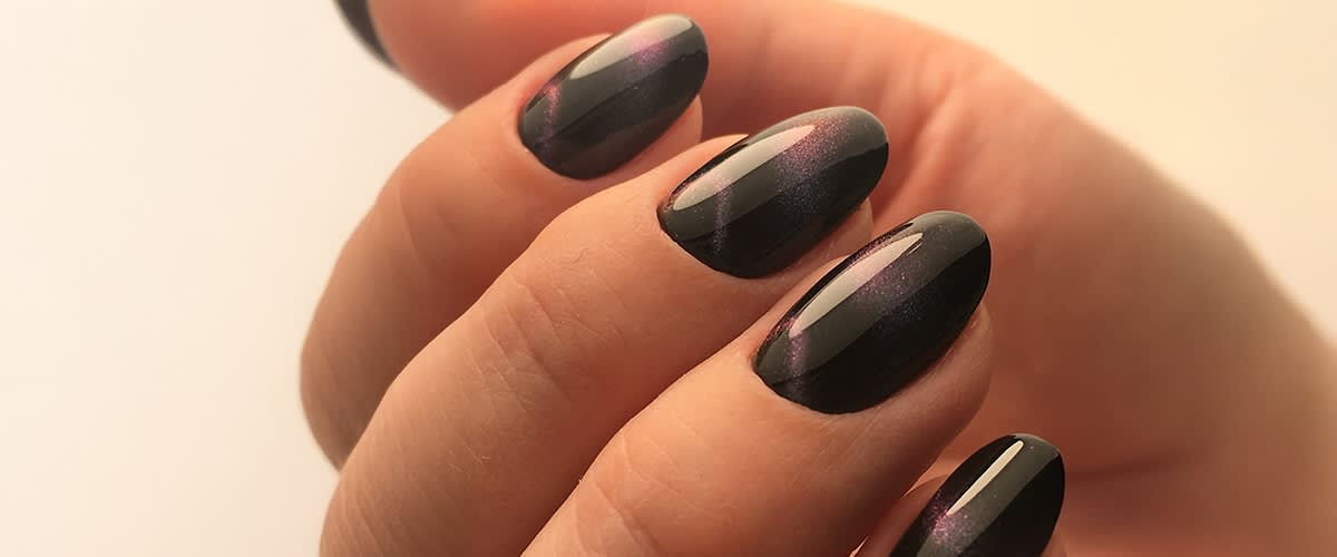 Nahaufnahme von fünf Fingern mit glänzendem, dunkelviolettem Nagellack und leichtem Schimmer