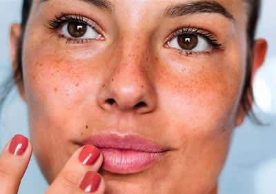 Eine Frau mit rotem Nagellack berührt ihre Lippen mit einem Finger