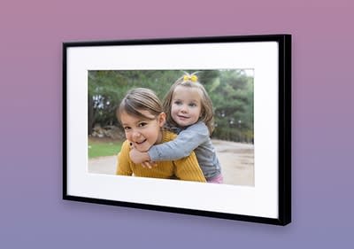 Ein gerahmtes Foto zeigt zwei Kinder, das vordere trägt einen senfgelben Pullover, das hintere ein graues Oberteil mit gelber Schleife im Haar