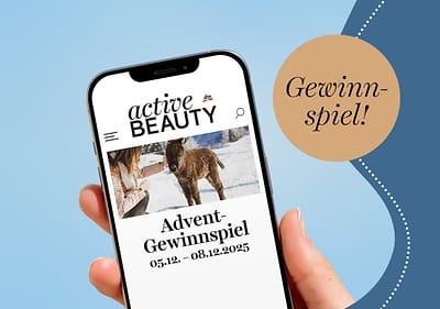 Eine Hand hält ein Smartphone mit der Webseite „active BEAUTY“ und dem Text „Advent-Gewinnspiel 05.12. - 08.12.2025“, daneben ein Kreis mit „Gewinnspiel!“