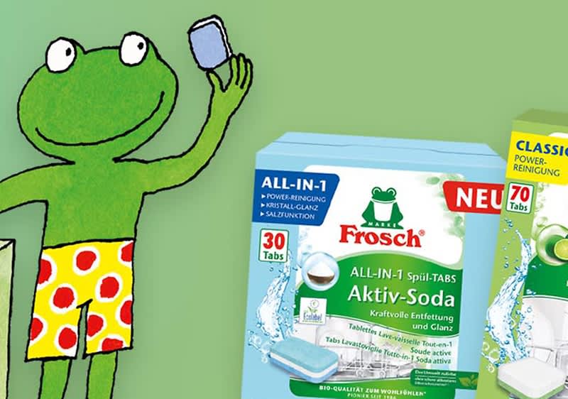 Eine Illustration zeigt einen grünen Frosch in gelber Hose mit roten Punkten, der ein Handy hält. Daneben eine Frosch-Produktverpackung.
