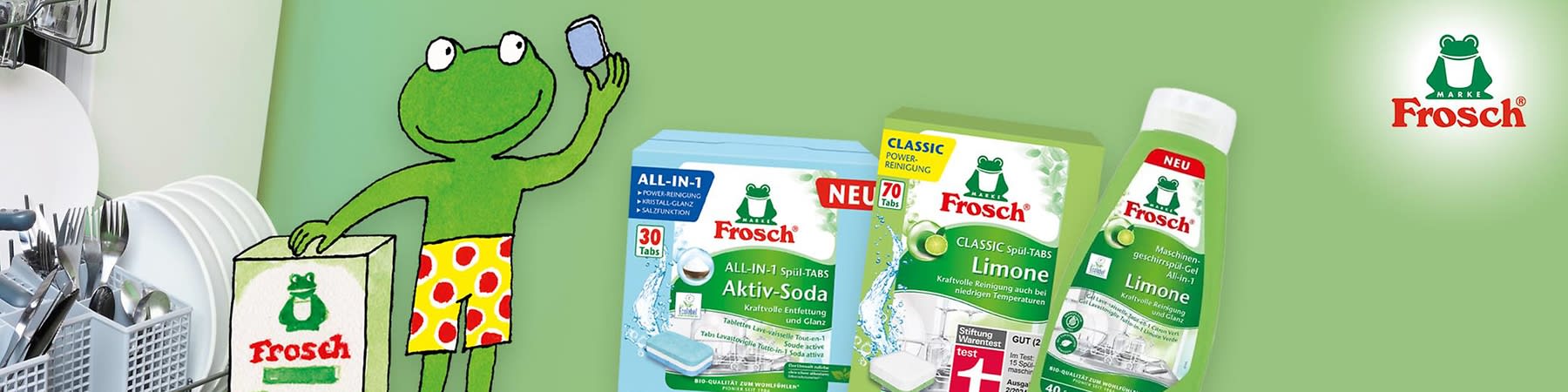 Eine Illustration zeigt einen grünen Frosch in gelber Hose mit roten Punkten, der ein Handy hält. Daneben eine Frosch-Produktverpackung.