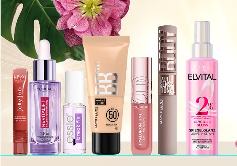 Mehrere Kosmetikprodukte vor einer Blume: Lippenstift, Serum, Nagellack, BB-Creme, Lippenpflege, Mascara und Haarpflege von verschiedenen Marken.