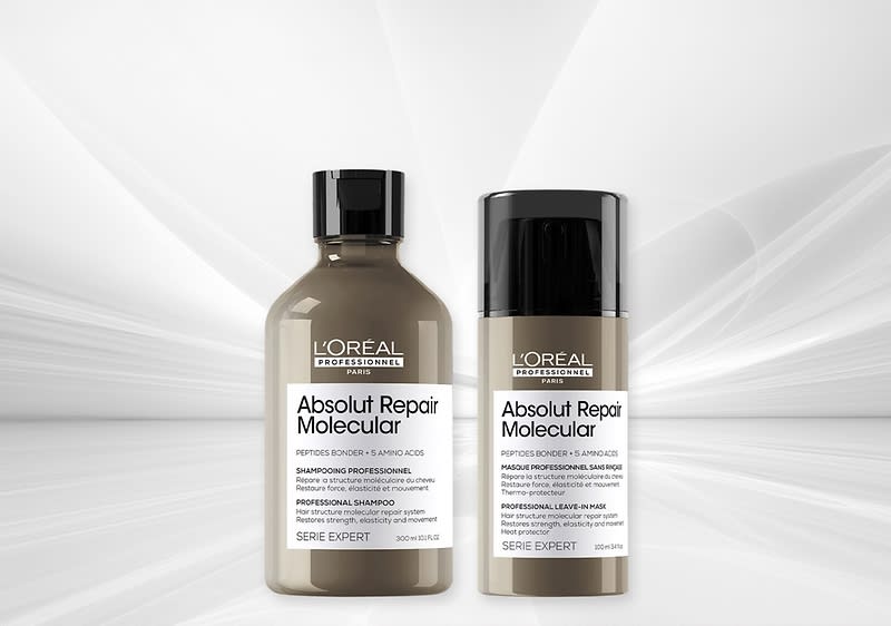 Zwei L'Oréal Professionnel Absolut Repair Molecular Produkte nebeneinander: links eine braune Shampoo-Flasche mit schwarzem Verschluss und weißem Etikett, rechts ein braunes Pump-Flakon mit schwarzem Deckel und weißem Etikett, auf hellem abstraktem Hintergrund
