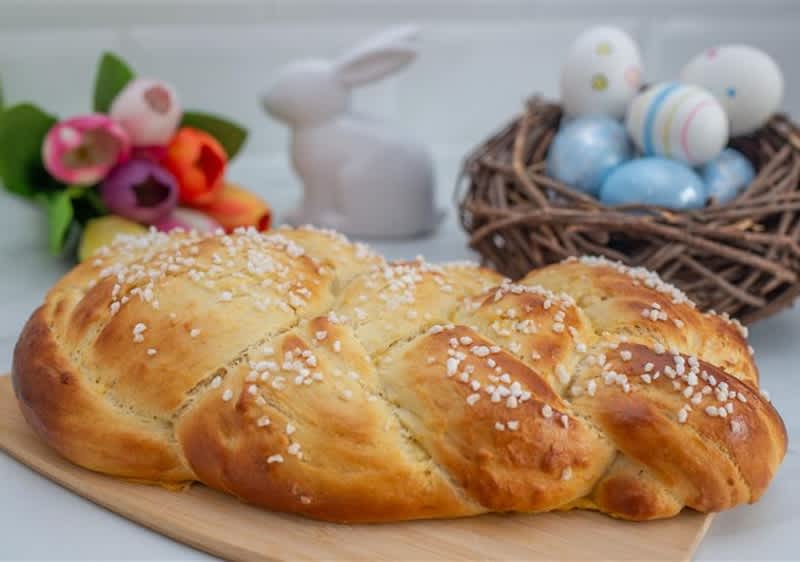 Ein Marmorkuchen mit Schokoladenüberzug zeigt im Anschnitt ein dunkles Hasenmuster. Daneben stehen gelbe Narzissen.