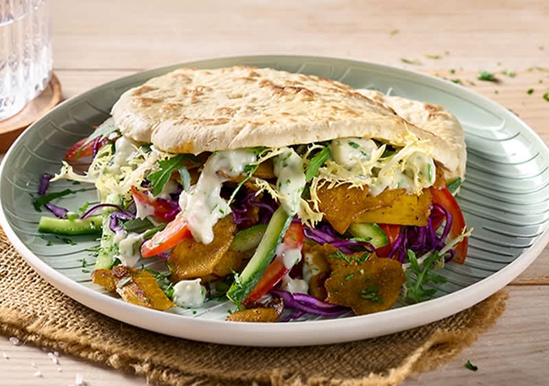 Gefülltes Fladenbrot mit veganen Zutaten auf einem grünen Teller
