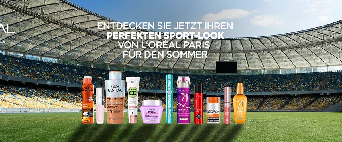 Auf einer Stadionrasenfläche vor Tribünenreihen zehn L’Oréal Paris Haar- und Stylingprodukte in Reihe, darüber weißer Text: „ENTDECKEN SIE JETZT IHREN PERFEKTEN SPORT-LOOK VON L’ORÉAL PARIS FÜR DEN SOMMER“
