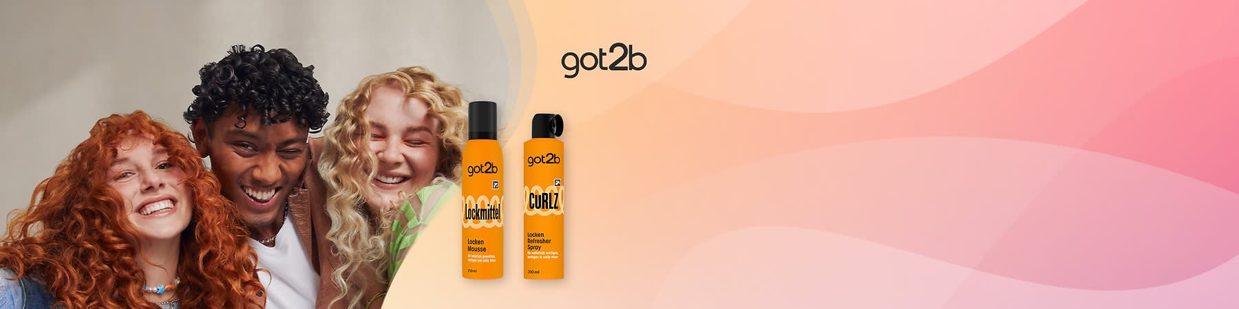 Zwei orangefarbene got2b Haarpflegeflaschen nebeneinander, links „Lockmittel Locken Mousse 200 ml“, rechts „Curly Locken Refresher Spray 200 ml“, vor rosa-beigem Hintergrund, got2b-Logo oben rechts