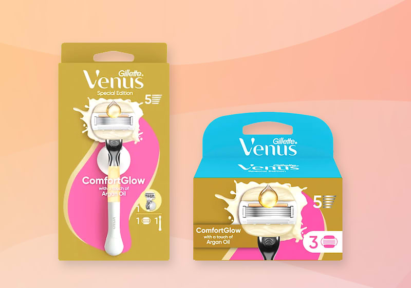 Zwei Verpackungen eines Gillette Venus ComfortGlow Rasierers mit Arganöl: links ein hochkantiges gold-rosa Blister mit weißem Griff und Klinge, rechts eine flache Kartonschachtel in Gold und Türkis mit Ersatzklingenpaket und dem Aufdruck „Venus“ und „ComfortGlow“
