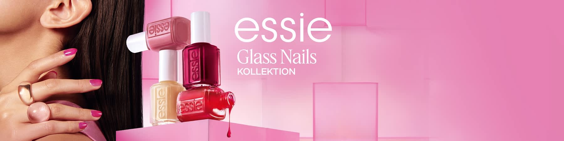 Vier Essie-Nagellackfläschchen in Pastellrosa, Creme, Dunkelrot und Korallenrot auf rosa gestufter Fläche, ein Tropfen roter Lack fällt, rechts Schriftzug essie Glass Nails KOLLEKTION