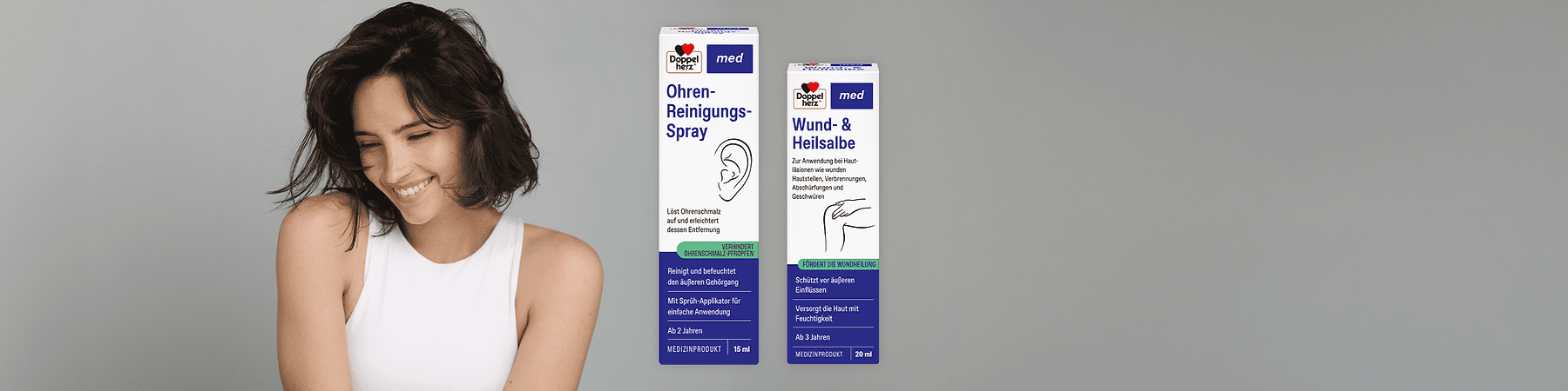 Zwei weiße Produktkartons der Marke Doppelherz nebeneinander; links Ohren-Reinigungs-Spray 15 ml mit Ohrillustration und blauer sowie grüner Textleiste, rechts Wund- & Heilsalbe 20 ml mit Hand-Illustration und blauer sowie grüner Textleiste