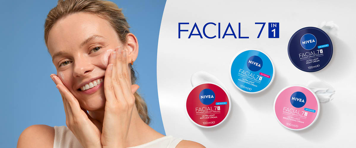 Lächelnde Frau trägt Gesichtscreme auf beide Wangen auf, rechts vier runde Nivea Facial 7in1 Tiegel in Blau, Dunkelblau, Rot und Rosa auf weißem Hintergrund und Schriftzug „FACIAL 7in1“