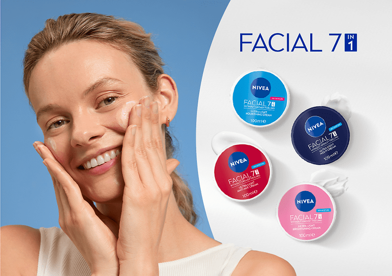 Lächelnde Frau trägt Gesichtscreme auf beide Wangen auf, rechts vier runde Nivea Facial 7in1 Tiegel in Blau, Dunkelblau, Rot und Rosa auf weißem Hintergrund und Schriftzug „FACIAL 7in1“