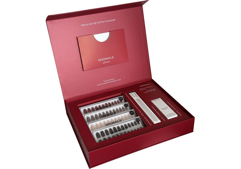Rotes Geschenkset mit dem Schriftzug „DOONAILS“ enthält vier Reihen künstlicher Fingernägel in verschiedenen Nude- und Rosenholz-Tönen sowie eine Feile und eine kleine weiße Produktbox, alles sauber einsortiert